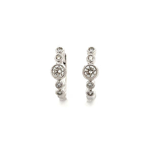 These dainty diamond bezel huggy earrings feature round brilliant c...
