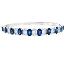 This 18k white gold bangle features diamonds and sapphires. The bag...