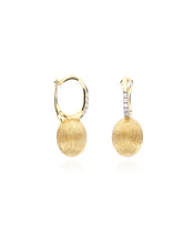 Elegant yellow gold and diamond earrings. The golden and uneven sur...