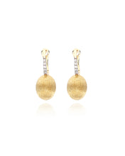 Elegant yellow gold and diamond earrings. The golden and uneven sur...