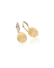 Elegant yellow gold and diamond earrings. The golden and uneven sur...