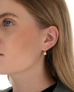 Elegant yellow gold and diamond earrings. The golden and uneven sur...