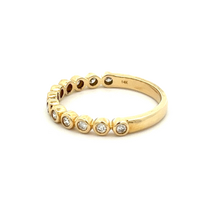 This stackable 14k yellow gold diamond band features 12 bezel set d...