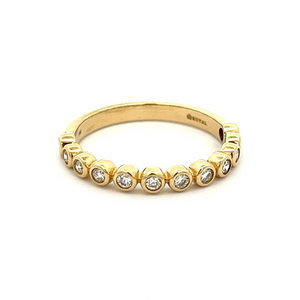This stackable 14k yellow gold diamond band features 12 bezel set d...