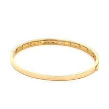 This 14k yellow gold bangle features round brilliant cut and baguet...