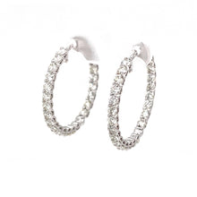 These small white gold hoops feature round brilliant cut diamonds t...