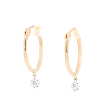 these oval shaped, yellow gold hoops feature round brilliant cut di...