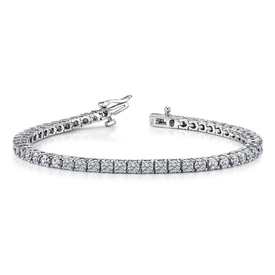 This diamond tennis bracelet features prong set round brilliant cut...