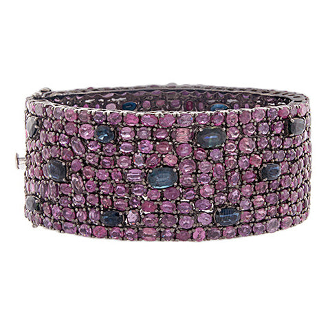 This one of a kind bangle features ruby and sapphires set all the w...