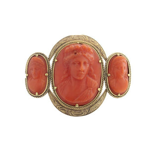 This brooch features three carved coral cameos set in 18k yellow gold.