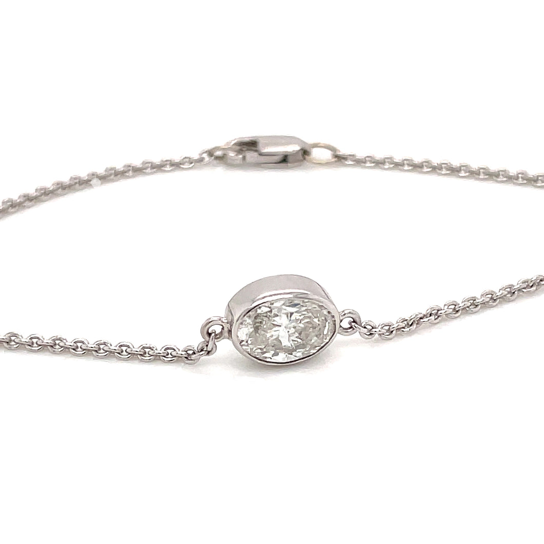 This bracelet is 14k white gold and features a bezel set oval cut d...