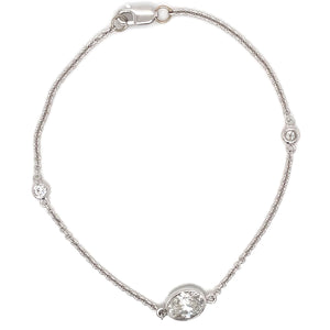 This bracelet is 14k white gold and features a bezel set oval cut d...